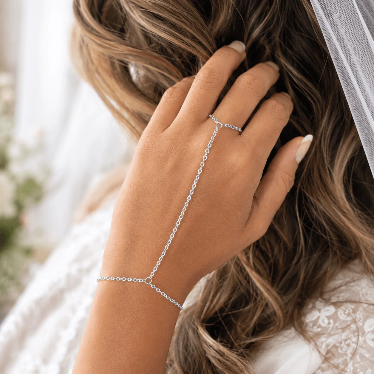 Delicate gold tone stainless steel hand chain draping from wrist to finger for elegant hand jewelry styling