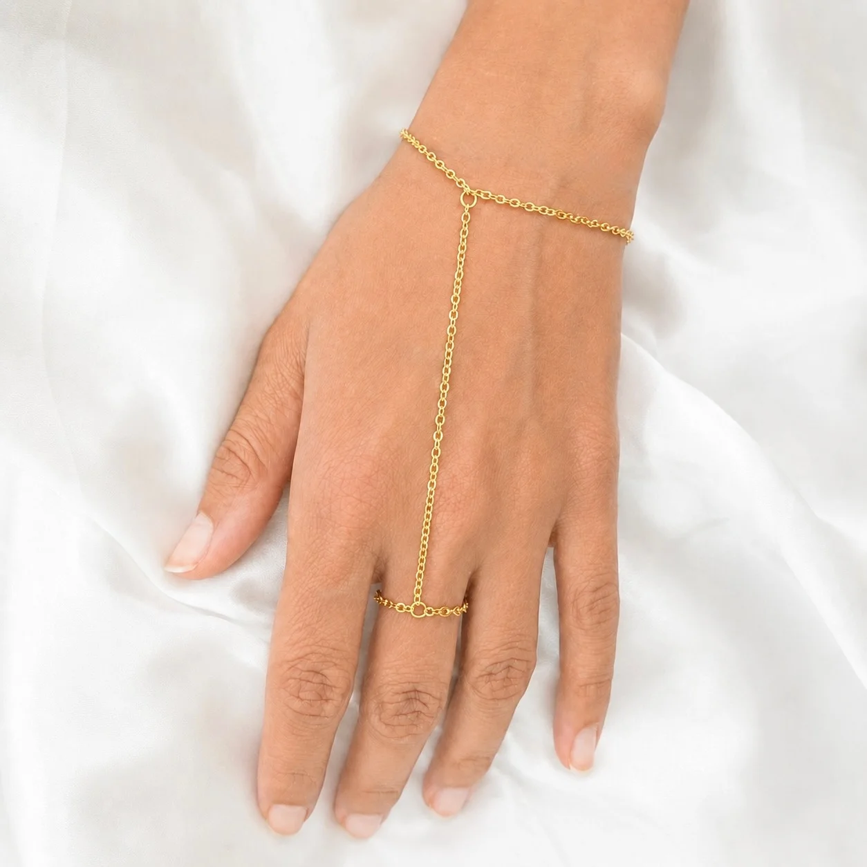 Delicate gold tone stainless steel hand chain draping from wrist to finger for elegant hand jewelry styling