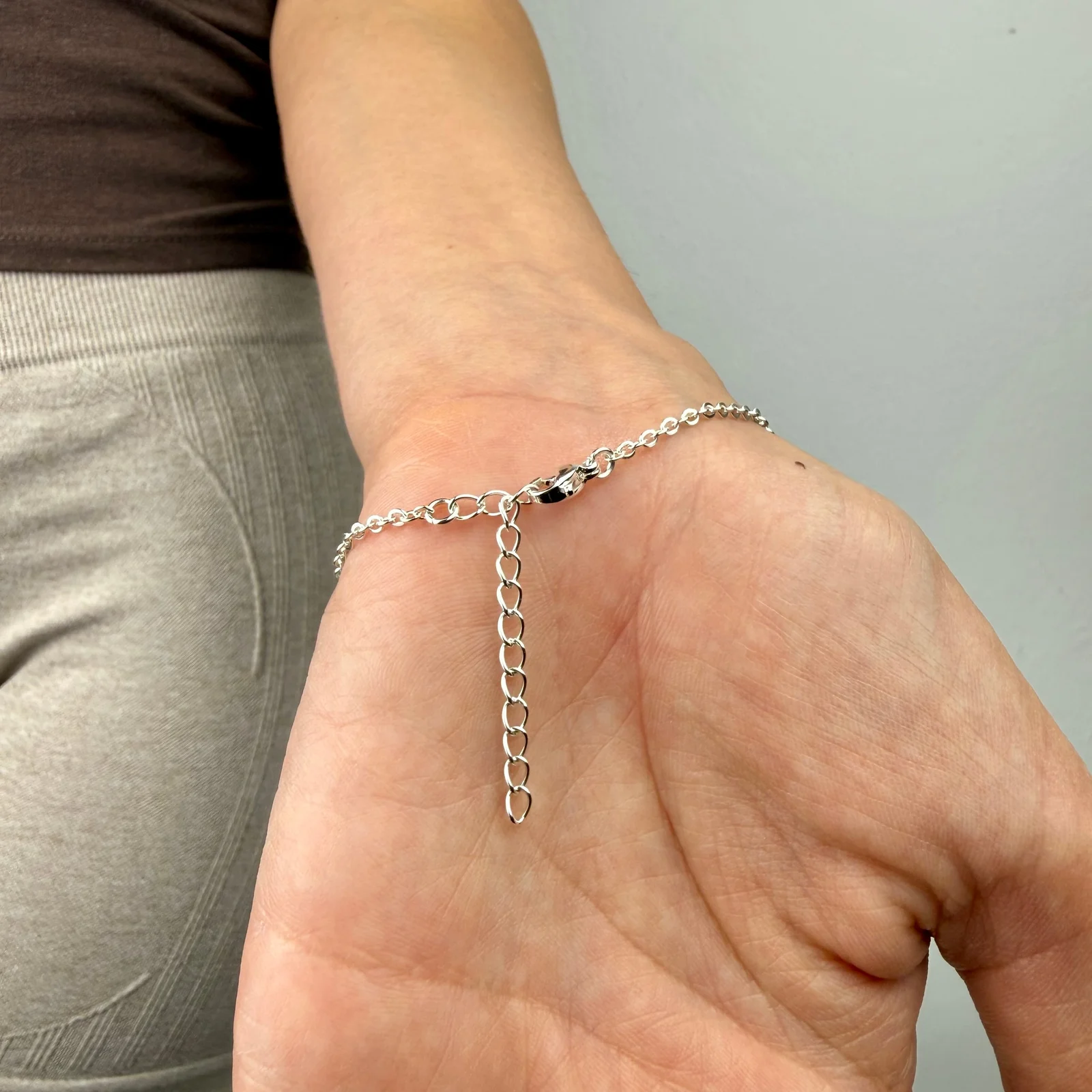 Delicate gold tone stainless steel hand chain draping from wrist to finger for elegant hand jewelry styling
