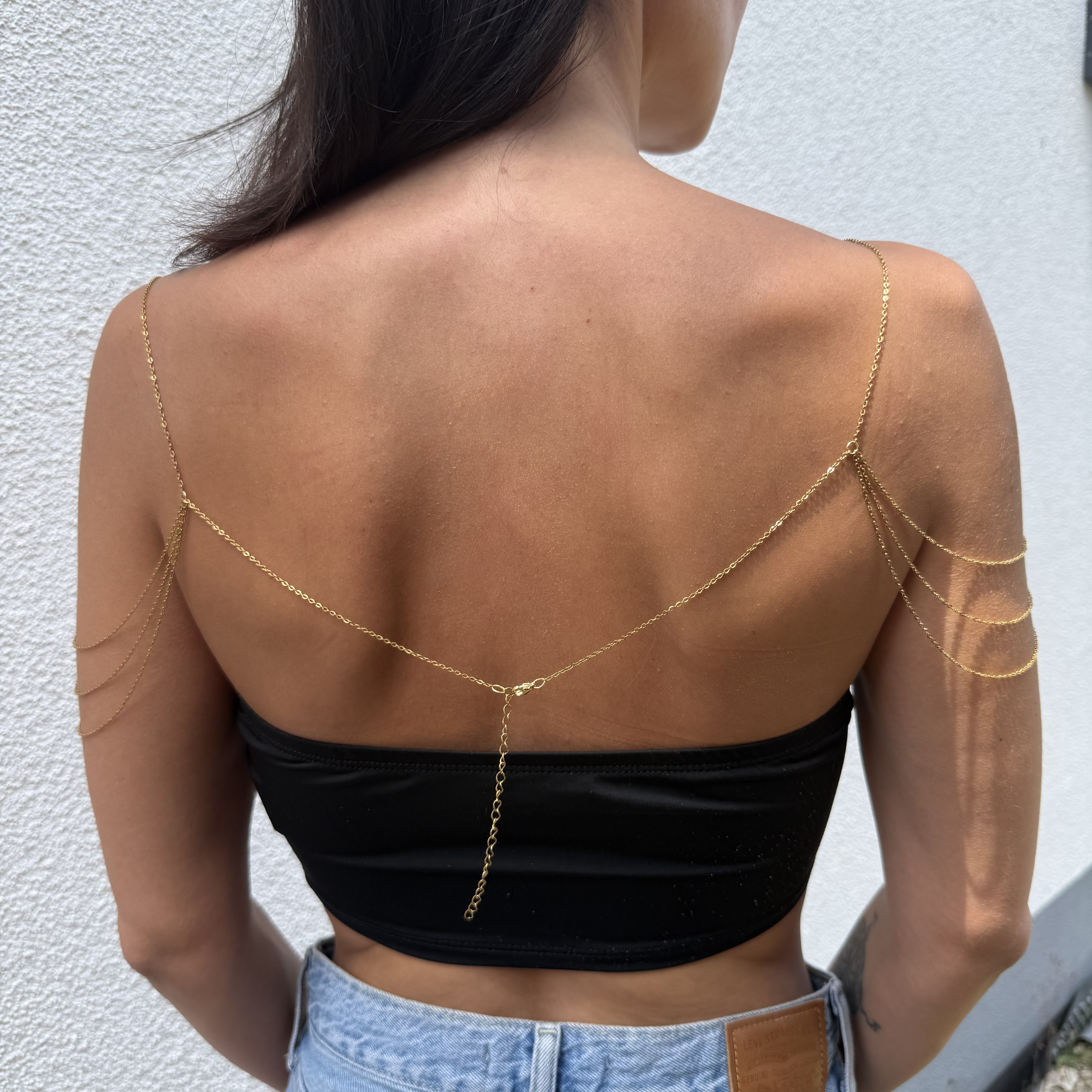 Delicate gold tone stainless steel shoulder chain draping across collarbone for layered chest jewelry styling