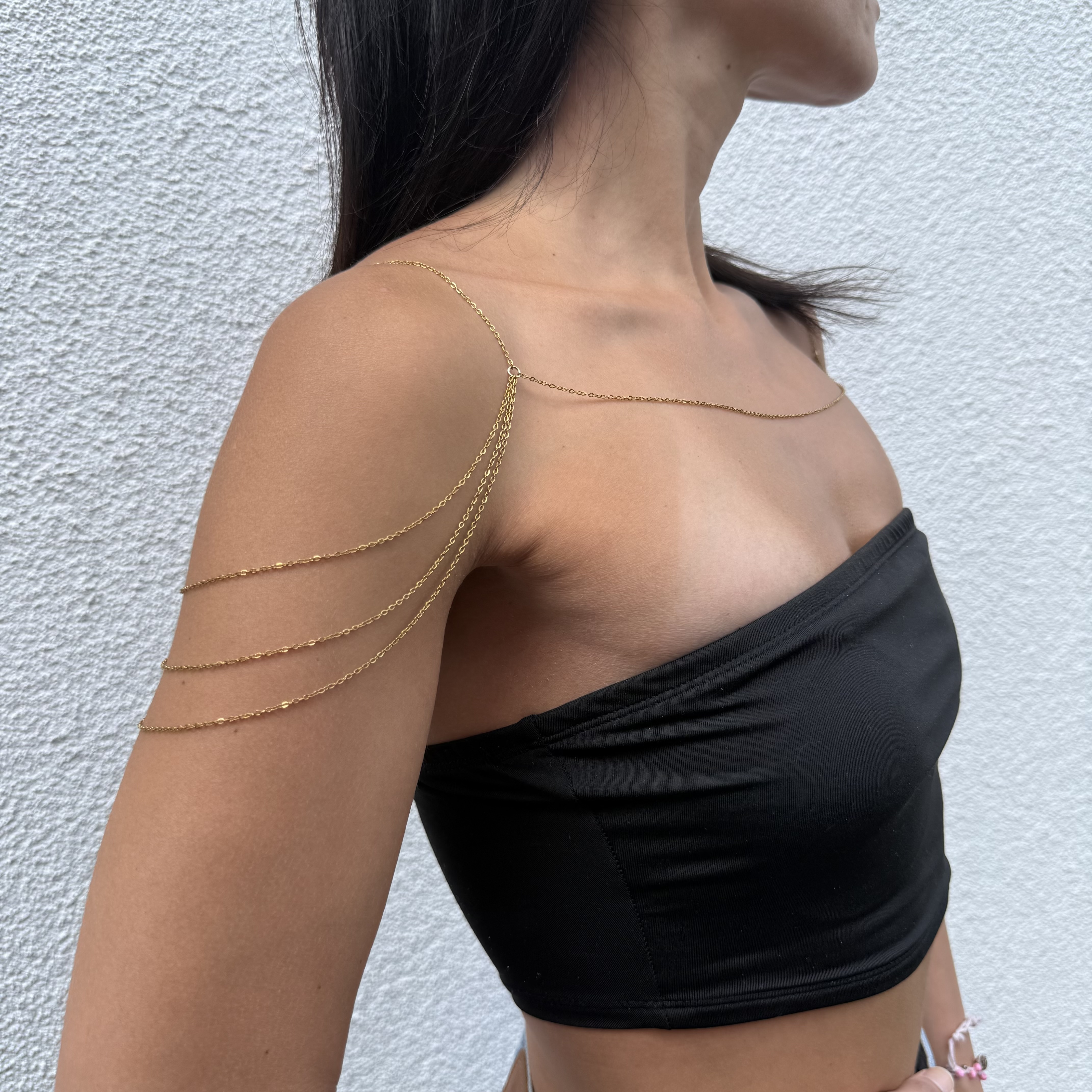 Delicate gold tone stainless steel shoulder chain draping across collarbone for layered chest jewelry styling
