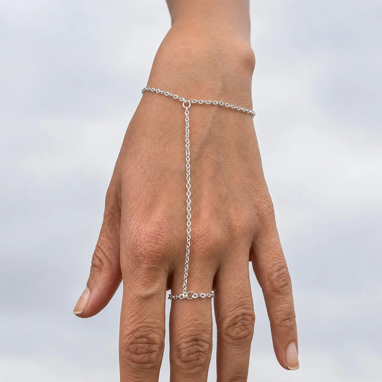 Delicate gold tone stainless steel hand chain draping from wrist to finger for elegant hand jewelry styling
