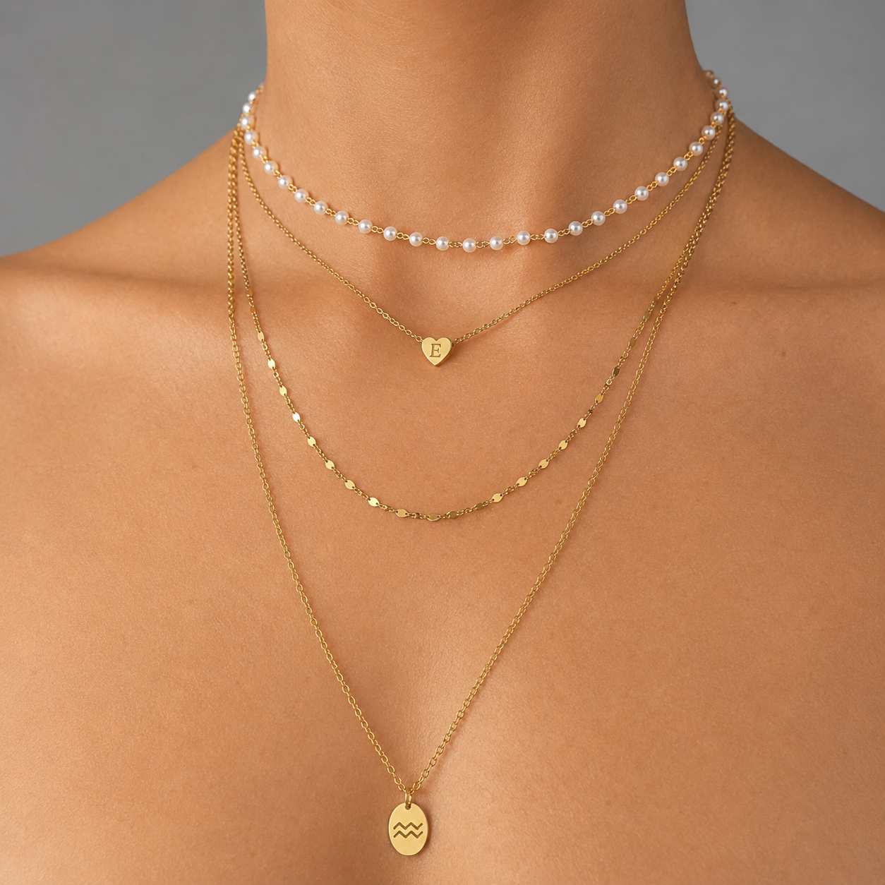Gold-tone stainless steel maximalist layered necklace stack with pearl choker, heart initial pendant, and zodiac charm